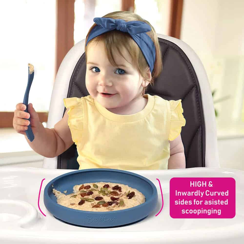 Baby girl with blue headband using silicone suction plate in high and curved sides.
